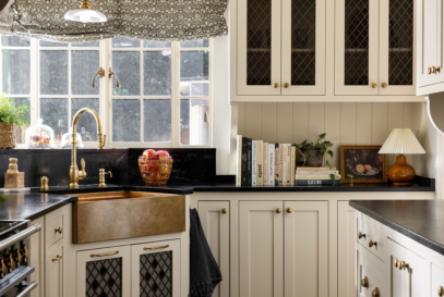 Charming kitchen photo showcasing beautiful mosaic floor, copper kitchen sink, floral roman shades, handmade cabinetry and hardware, styled with houseplants, cookbooks and found kitchen accessories.